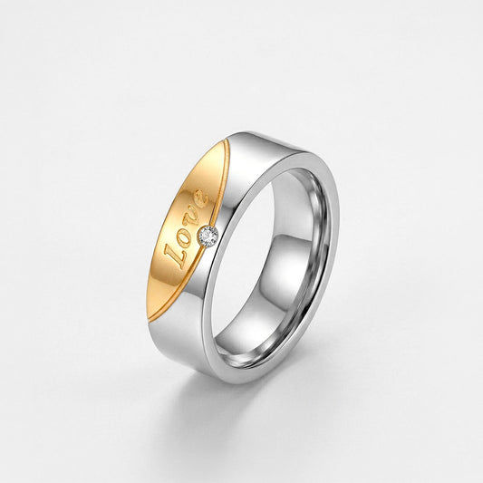 Anillo para dama bicolor de titanio enchapado en oro con grabado Love y piedra brillante central, fondo blanco - Codigo 5360