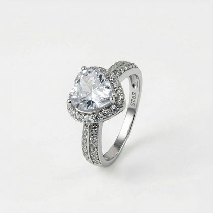 Anillo de compromiso de plata ley 925 con piedra en forma de corazón y pedrería alrededor, sobre fondo blanco - producto de Joyería Monael