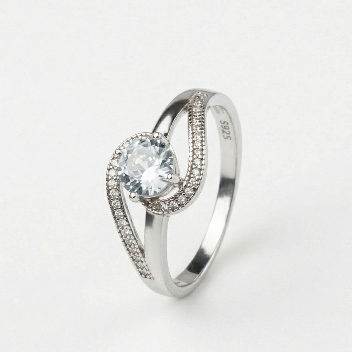Anillo de compromiso de plata ley 925 con diseño curvo con pedrerías incrustadas, sobre fondo blanco - producto de Joyería Monael