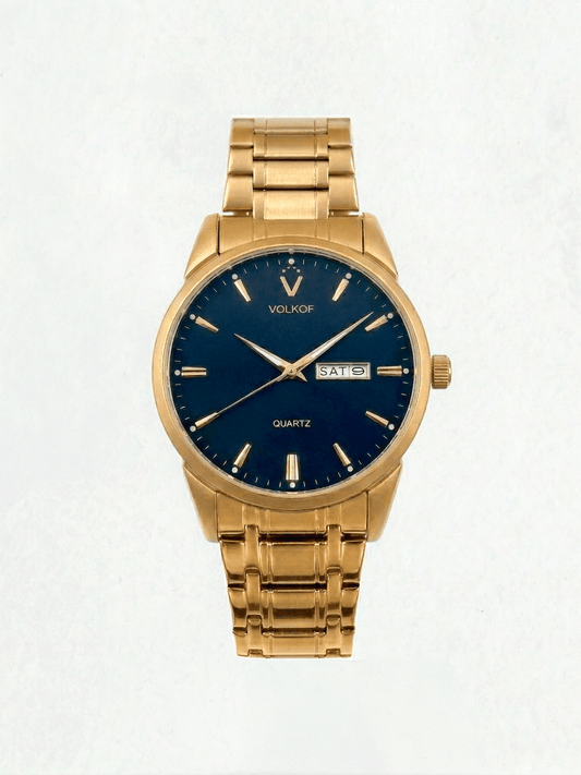 Reloj analógico para hombre en acero inoxidable color oro, esfera azul oscuro mate con índices lineales dorados, doble ventana de fecha y día, y brazalete de eslabones dorados